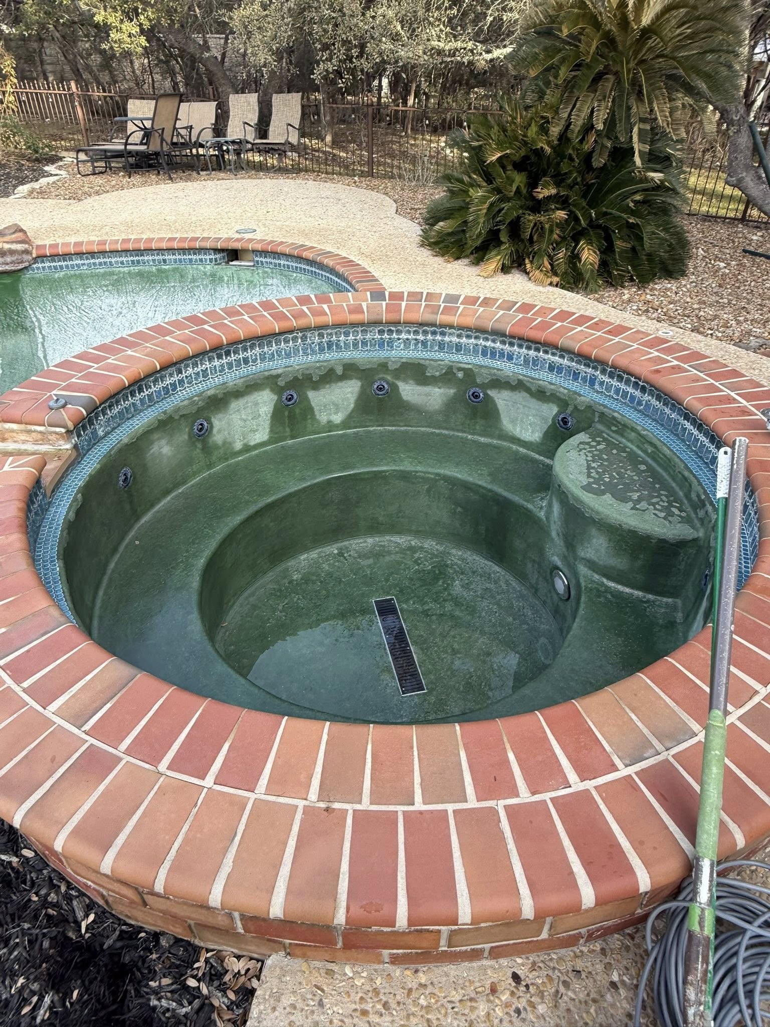 Finished spa with green pebble and brick coping